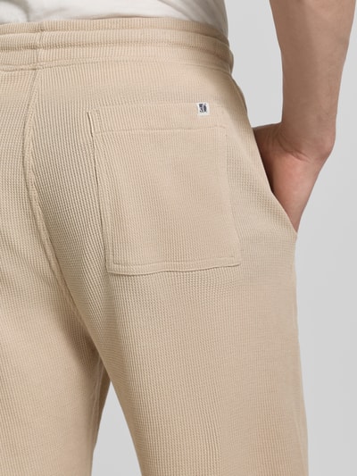 Männermodel trägt Relaxed Fit Sweatshorts aus Baumwoll-Mix von s.Oliver RED LABEL in Beige, strukturiert, Piqué, Nahaufnahme Rückansicht.