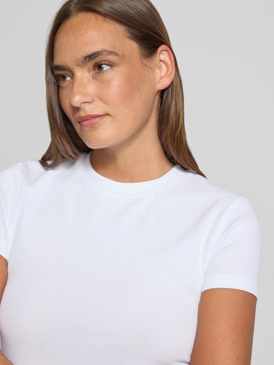 Kobieta modelka nosi damski t-shirt z mieszanki bawełny i elastanu Stefanel Slim Fit model 'COSTINA' z okrągłym dekoltem, długość tyłu w rozmiarze S: 55 cm, biała gładka tkanina, prosty krój, nahaufnahme górnej części ciała.