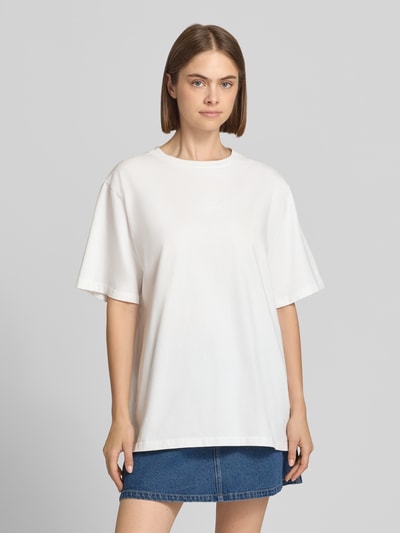 Frauenmodel trägt Oversized T-Shirt mit rückseitigem Stitching Modell 'Flower' von OH APRIL in Weiß aus reiner Baumwolle, Rundhalsausschnitt, Ganzkörperansicht von vorne.