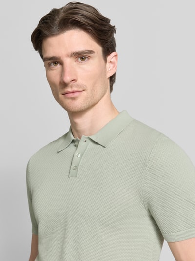Männermodel trägt Slim Fit Poloshirt in Strick-Optik Modell 'TRITON' von Drykorn, hellgrün, reine Baumwolle, Nahaufnahme Oberkörper.