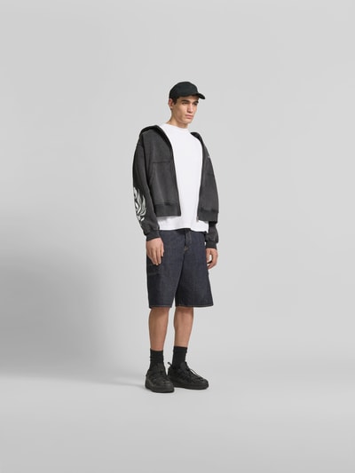 Männermodel trägt Oversized Sweatjacke aus Baumwolle von Don´t Waste Culture in Dunkelgrau mit Känguru-Tasche und Reißverschluss, Ganzkörperansicht von vorne. Rückenlänge 63 cm, Schulterbreite 55 cm, Ärmellänge 65 cm.