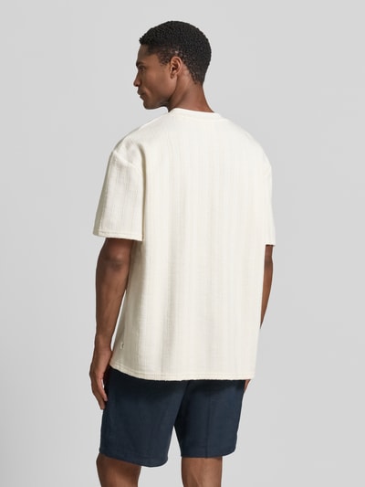 Männermodel trägt T-Shirt mit Strukturmuster und Rundhalsausschnitt von Les Deux aus Material-Mix mit Viskose-Anteil, Regular-Fit, Rückenlänge bei Größe M 67 cm, helles Beige, lockere Textur, Ganzkörperansicht Rückansicht.