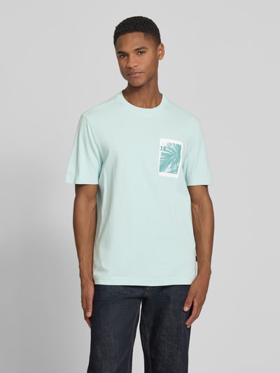 Männermodel trägt Regular Fit T-Shirt aus reiner Baumwolle Modell 'TE_BOARD' von BOSS Orange, Optik: Unifarben, Foto-Print, Ganzkörperansicht von vorne.