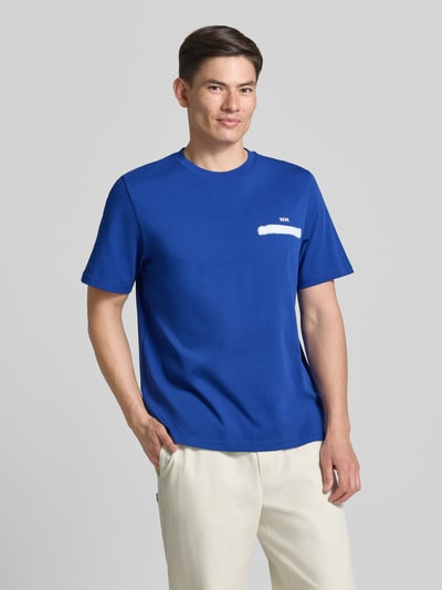 Männermodel trägt T-Shirt mit rückseitigem Motiv-Print Modell 'Bobby' von Wood Wood in Blau, Regular Fit, aus Baumwolle, Ganzkörperansicht von vorne.