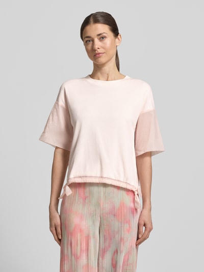 Frauenmodel trägt T-Shirt mit Rundhalsausschnitt und Tunnelzug von Marc Cain aus Baumwoll-Elasthan-Mix, Relaxed-Fit, Ärmel mit Aufschlag, Rückenlänge 51 cm bei Größe 36, sanfte Pastellfarben, strukturierte Optik, Ganzkörperansicht von vorne.