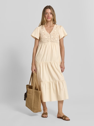 Frauenmodel trägt Midikleid im Stufen-Look mit Häkelspitze Modell 'SANDY' von Bash aus reiner Baumwolle in A-Linie, V-Ausschnitt, Knopfleiste, helle Beige-Töne, strukturierte Oberfläche, Ganzkörperansicht von vorne. Rückenlänge bei Größe S: 120 cm, Brustweite: 42 cm, Ärmellänge: 20 cm.