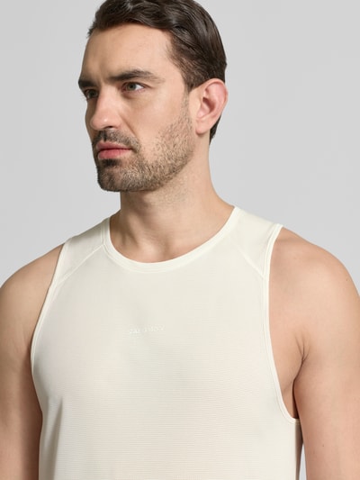 Männermodel trägt Tanktop mit Rundhalsausschnitt und Logo von Salomon in Creme, Regular Fit, feine Struktur, Nahaufnahme Oberkörper.