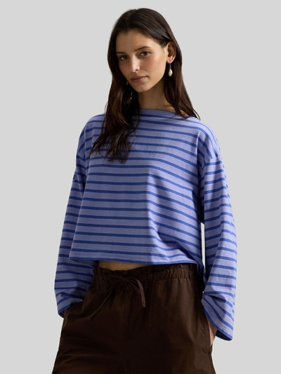 Frauenmodel trägt Oversized Pullover aus reiner Baumwolle von Polo Ralph Lauren, lila-blau gestreift, U-Boot-Ausschnitt, Ganzkörperansicht von vorne.