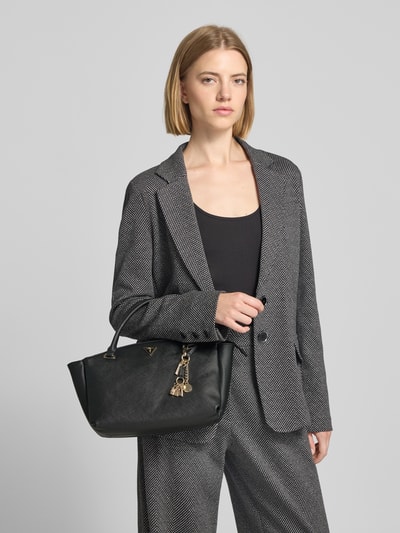 Frauenmodel trägt Tote Bag aus Leder-Imitat Modell 'Gilda' von GUESS, schwarz, mit Logo-Detail, Ganzkörperansicht von vorne.