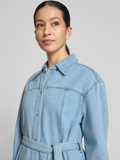 Vrouwenmodel draagt knielang denimjurk in lichtblauw katoenmix, recht model, overhemdkraag, strikceintuur, model 'Kimmia' van mbyM, borstwijdte 58 cm, mouwlengte 62 cm, ruglengte 93 cm, detailopname bovenlichaam.