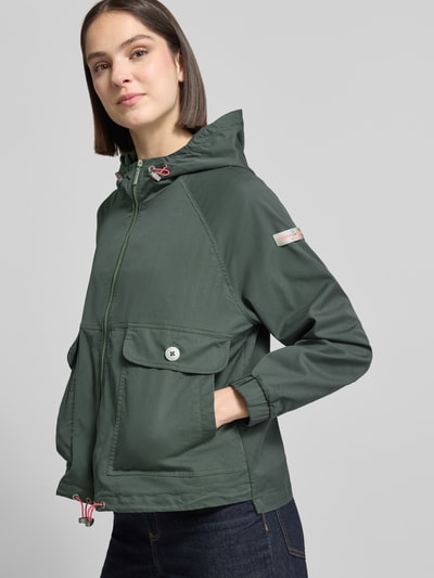 Kobiece modelka nosi kurtka Jacke mit Zweiwege-Reißverschluss Modell 'DOLORES NEO' od Frieda & Freddies, mieszanka bawełny, prosty krój, kaptur z blokadą sznurka, zamek błyskawiczny dwustronny, naszywka z logo, kieszenie z patką i zapięciem na guzik, elastyczne zakończenia rękawów, regulowany dół, długość tyłu 59 cm, szerokość ramion 48 cm, szerokość w rozmiarze 50 cm, długość rękawów 52 cm; widok całej sylwetki z przodu