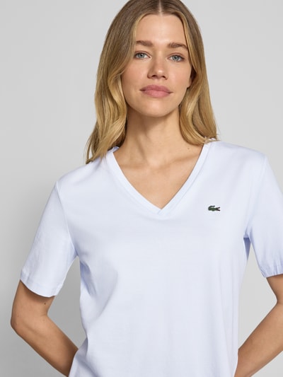 Frauenmodel trägt Relaxed Fit T-Shirt aus reiner Baumwolle von Lacoste, Optik: Unifarben, Logo-Stitching, V-Ausschnitt, Nahaufnahme Oberkörper.
