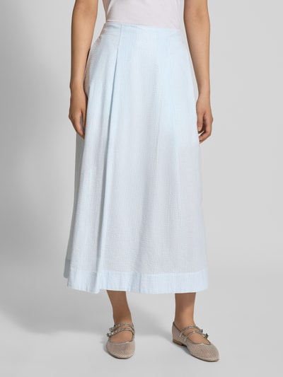 Frauenmodel trägt Ausgestellter Midi-Rock aus reiner Bio-Baumwolle Modell 'HANNAH' von Selected Femme im hellblauen Allover-Muster, Seersucker-Struktur, seitliche Eingrifftaschen und elastischer Bund, Regular Fit, Ganzkörperansicht von vorne.