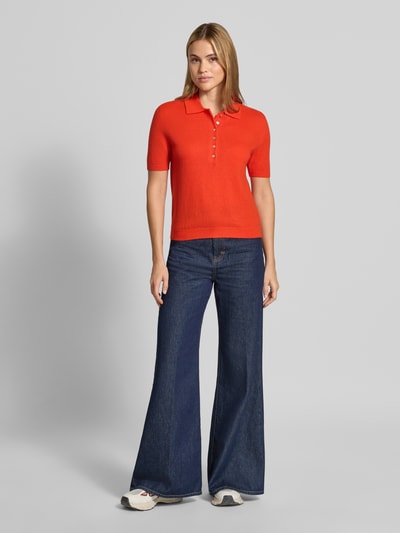 Frauenmodel trägt Poloshirt aus reiner Wolle von Stefanel in Rot, taillierte Passform, gerippte Abschlüsse, Ganzkörperansicht von vorne.