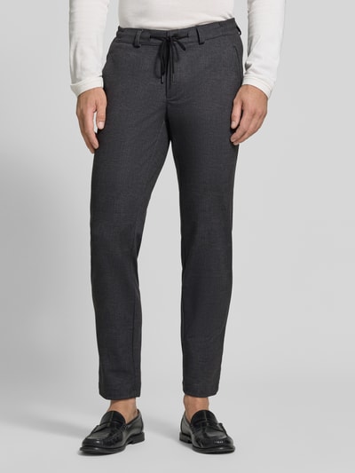 Männermodel trägt dunkelgraue Tapered Fit Jogpants aus reiner Baumwolle Modell 'Phil' von Brax, Herren Weite Hose, Ganzkörperansicht von vorne.
