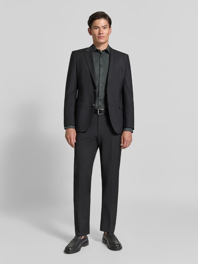Männermodel trägt Super Slim Fit Businesshemd aus Baumwoll-Mix von OLYMP No. Six in Dunkelgrün, schwarze Anzughose, Ganzkörperansicht von vorne.