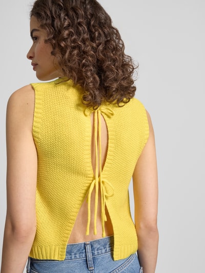 Frauenmodel trägt Regular Fit Weste mit Logo-Stitching von ANOTHER COTTON LAB in Strick-Optik, gelb, Rundhalsausschnitt, Rückenlänge 39 cm, Ganzkörperansicht Rückansicht.