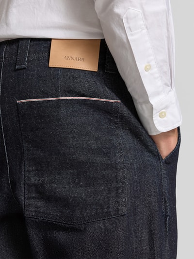 Männermodel trägt Relaxed Fit Jeans aus reiner Baumwolle von ANNARR, dunkelblauer Denim, sichtbare Gesäßtasche, Nahaufnahme Rückansicht.