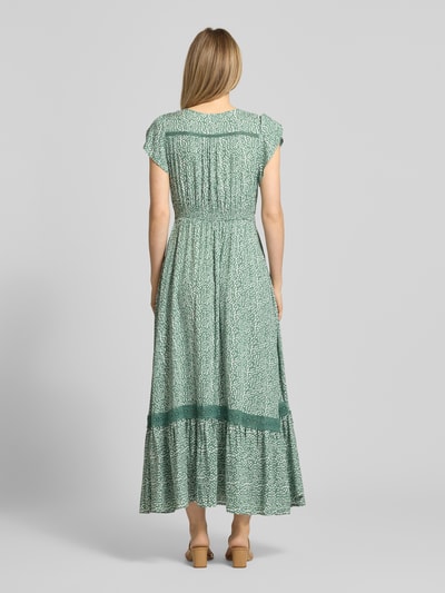 Modelka kobieca ma na sobie Midikleid aus Viskose mit Knopfleiste od Apricot, zielony nadruk allover, dekolt V, krój A-linia, czysta wiskoza, długość tyłu w rozmiarze S: 114 cm, szerokość w rozmiarze S: 32 cm, długość rękawa w rozmiarze S: 10 cm, widok całej sylwetki z tyłu.