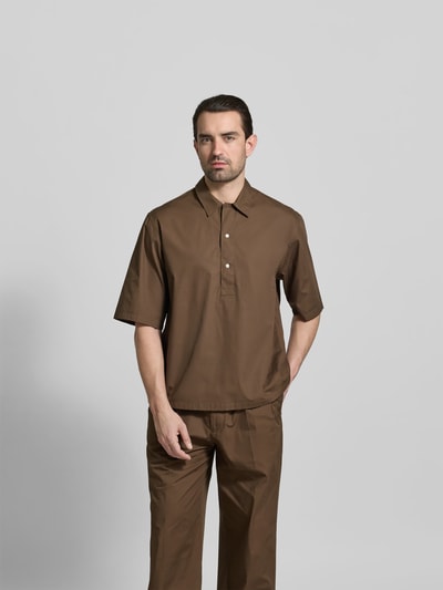Männermodel trägt Relaxed Fit Freizeithemd mit Kentkragen von Officine Générale aus reiner Baumwolle, braun, Knopfleiste, Halbarm, Ganzkörperansicht von vorne.