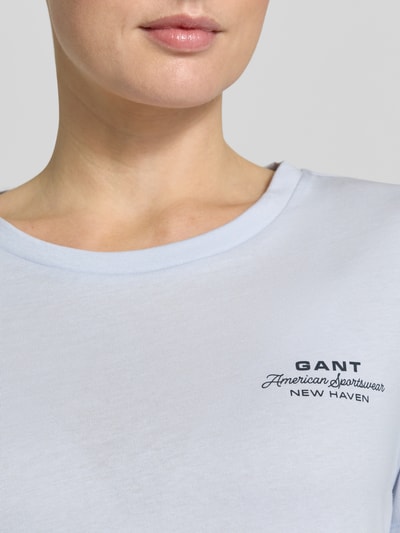 Vrouwenmodel draagt T-shirt met Label-Print en Rundhalsausschnitt van Gant, puur katoen, regular fit, ruglengte bij maat S 57 cm, Nahaufnahme bovenlichaam.