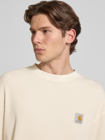 Männermodel trägt T-Shirt mit Strukturmuster Modell 'Nelson' von Carhartt Work In Progress in Creme, Reine Baumwolle, Label-Detail, Rundhalsausschnitt, Relaxed-Fit, Nahaufnahme Oberkörper.