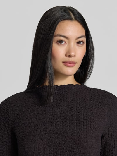 Frauenmodel trägt Regular Fit Langarmshirt aus Baumwoll-Mix Modell 'ZIA' von VERO MODA, schwarz, strukturierte Oberfläche, Nahaufnahme Oberkörper, Damen Langarmshirt von VERO MODA.