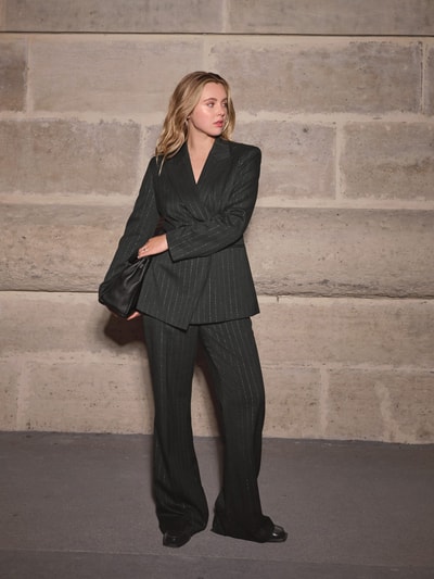 Frauenmodel trägt Anzughose mit Lurex-Nadelstreifen – curated by Isabelle Hartmann von Style Icon Collection, spodnie materiałowe z wiskozy, rozkloszowany krój, kanty, kieszenie z wypustkami, zapięcie na haftkę i zamek błyskawiczny, szerokość w pasie 38 cm, długość wewnętrzna nogawki 81 cm, materiał z prążkami i metalicznym połyskiem, kolor czarny, gładka tekstura, ganzkörperansicht von vorne.