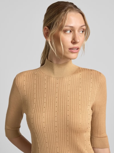 Frauenmodel trägt Slim Fit Longsleeve aus reiner Lanawolle Modell 'Maglia Costine' von Liu Jo White in Beige mit Stehkragen, Halbarm, semitransparent, Nahaufnahme Oberkörper.