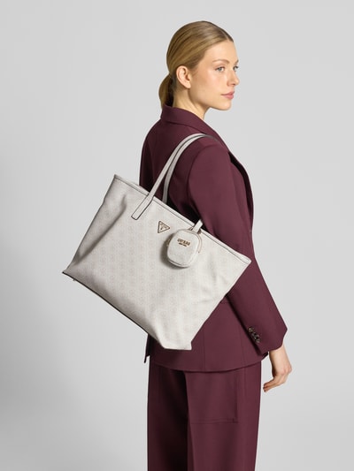 Frauenmodel trägt Shopper mit Logo-Muster Modell 'ECO POWER PLAY II' von Guess, hellgrau, strukturierte Oberfläche, Tragehenkel, herausnehmbare Innentasche, Hauptfach mit Reißverschluss, Ganzkörperansicht Rückansicht.