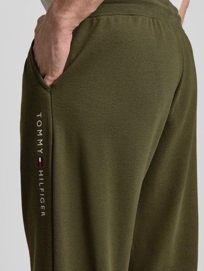 Männermodel trägt olivgrüne Comfort Fit Sweatpants aus katoenmix van Tommy Hilfiger met label stitching, sweatstof, detailaufnahme linker heup.