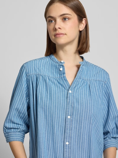 Frauenmodel trägt Regular Fit Bluse aus reiner Baumwolle Modell 'LIVIA' von Pepe Jeans in Denim-Optik mit Maokragen, Knopfleiste, 3/4-Arm, feine weiße Streifen, glatte Textur, Nahaufnahme Oberkörper.
