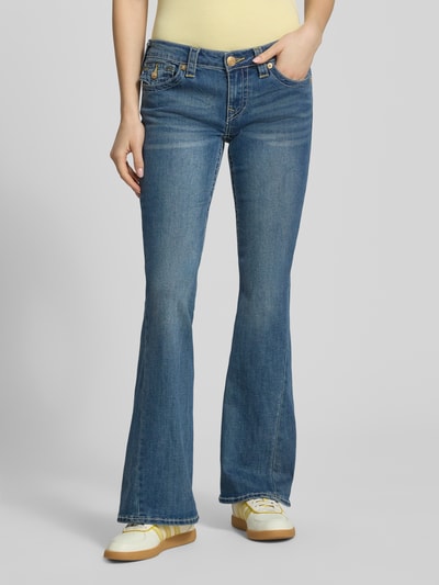 Frauenmodel trägt Low Rise Flared Jeans mit Eingrifftaschen Modell 'JOEY' von TRUE RELIGION aus Baumwoll-Mix im Used-Look, Ganzkörperansicht von vorne.