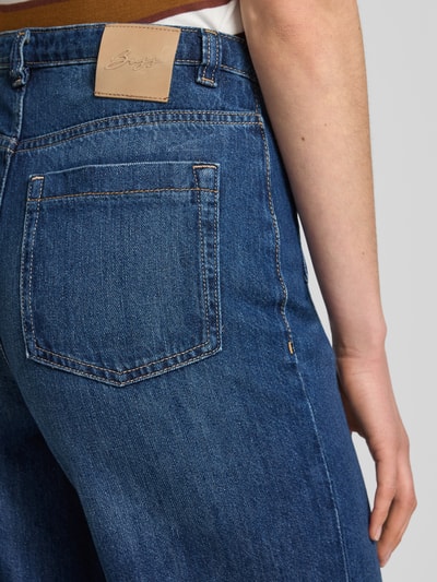 Frauenmodel trägt Flared Jeans aus Baumwoll-Mix Modell 'C_MARLENE' von BOSS Orange mit Gesäßtasche, Label-Patch, blaue Denim-Optik, Nahaufnahme Oberkörper.