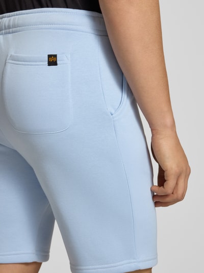 Mannenmodel draagt Shorts met Eingrifftaschen und Logo-Print van Alpha Industries in lichtblauw katoenmix, relaxed fit, detailopname achterzijde.