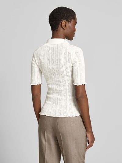Frauenmodel trägt Slim Fit Poloshirt in Strick-Optik von Victoria Beckham aus Baumwoll-Mix, semitransparent, kurzärmelig, Rückenlänge 56 cm, helle Farben, feine Muster, Ganzkörperansicht Rückansicht.