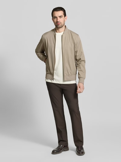 Męski model nosi bomberkę z prostym krojem, stójką, kieszeniami zapinanymi na zamek błyskawiczny, model 'MATTE' od CK Calvin Klein, długość tyłu 67 cm, szerokość ramion w rozmiarze M: 47 cm, szerokość klatki piersiowej w rozmiarze M: 58 cm, długość rękawów w rozmiarze M: 68 cm, widok całej sylwetki z przodu