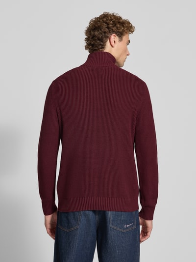 Männermodel trägt Slim Fit Strickpullover aus reiner Baumwolle mit Troyer-Kragen von MCNEAL in Dunkelrot, gerippte Abschlüsse, Ganzkörperansicht Rückansicht. Rückenlänge 72 cm, Ärmellänge 74 cm, langärmliges Design.