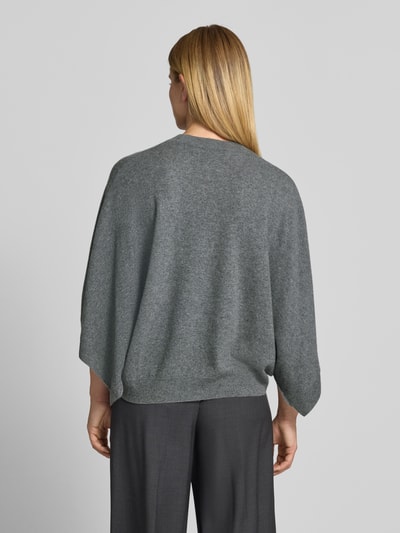 Frauenmodel trägt Relaxed Fit Pullover aus reinem Kaschmir in Strick-Optik von HERZENS, graue Farbe, elastischer Bund, Ganzkörperansicht Rückansicht.