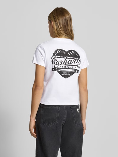Frauenmodel trägt T-Shirt mit Label-Detail von Carhartt Work In Progress in Weiß, Reine Baumwolle, Gerader Schnitt, Rückenlänge 49 cm, Ganzkörperansicht Rückansicht.