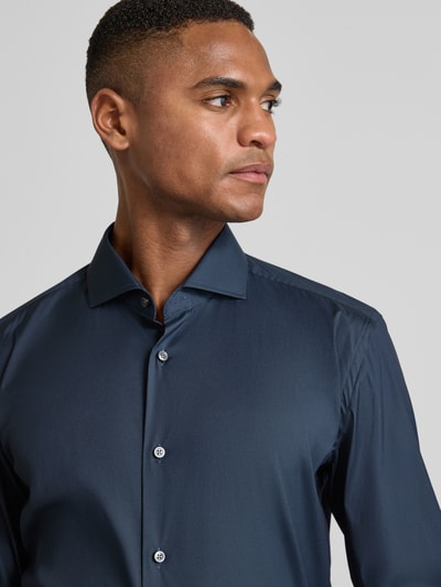 Männermodel trägt Slim Fit Business-Hemd mit Stretch-Anteil Modell 'Hank Hai' von BOSS, unifarben, Haifischkragen, Nahaufnahme Oberkörper.