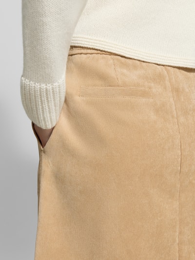 Frauenmodel trägt Regular Fit Mini-Rock in Cord-Optik von OPUS in Beige mit dezenter Struktur, Nahaufnahme Hüfte und Handtasche.