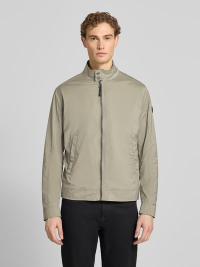 Männermodel trägt Jacke mit Stehkragen Modell 'Vicente' von JOOP! Collection in Beige, glatte Struktur, Reißverschluss, Eingrifftaschen, Ganzkörperansicht von vorne.