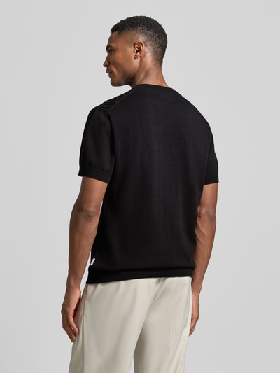 Männermodel trägt T-Shirt mit Zopfmuster von Lindbergh in Schwarz aus Baumwolle, gerader Schnitt, Strick-Optik, Rückansicht Ganzkörperansicht.