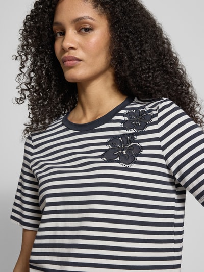 Kobiece modelka ma na sobie T-shirt aus Baumwoll-Mix od Christian Berg Woman Selection, biało-czarne paski, obszycie z kamieni stras, mieszanka bawełny i elastanu, prosty krój, półrękaw, okrągły dekolt, długość tyłu w rozmiarze 36: 54 cm, zbliżenie na górną część ciała.