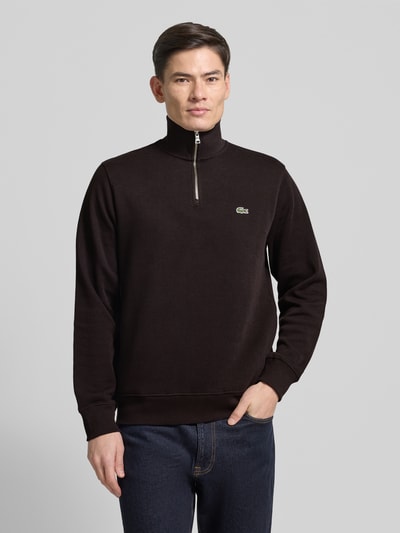 Männermodel trägt Regular Fit Troyer aus reiner Baumwolle von Lacoste, Optik: Unifarben, Logo-Patch, Strick, Langarm, Ganzkörperansicht von vorne.