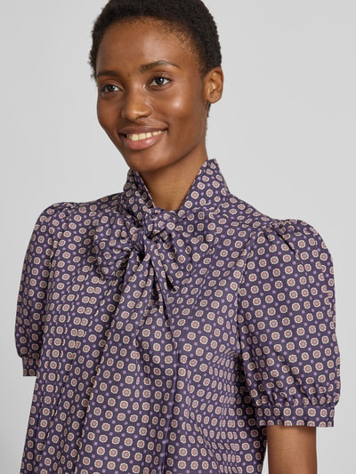 Frauenmodel trägt Regular Fit Schluppenbluse im Allover-Look von Rich & Royal, reine Baumwolle, gelegte Falten, Puffärmel, Nahaufnahme Oberkörper.