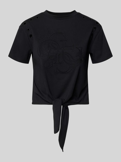 Frauenmodel trägt Regular Fit T-Shirt mit Lochmuster von Guess in Schwarz, Reine Baumwolle, Logo-Stitching, Rundhalsausschnitt, Rückenlänge 46 cm, Ganzkörperansicht von vorne.