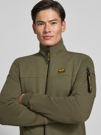 Männermodel trägt Sweatjacke mit Stehkragen und Label-Patch von PME Legend in Olivgrün, Strukturmuster, Nahaufnahme Oberkörper.