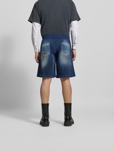 Männermodel trägt Baggy Fit Jeansshorts aus Baumwolle von Dsquared2, dunkelblau mit Label-Detail, Gesäßtaschen, Ganzkörperansicht Rückansicht.